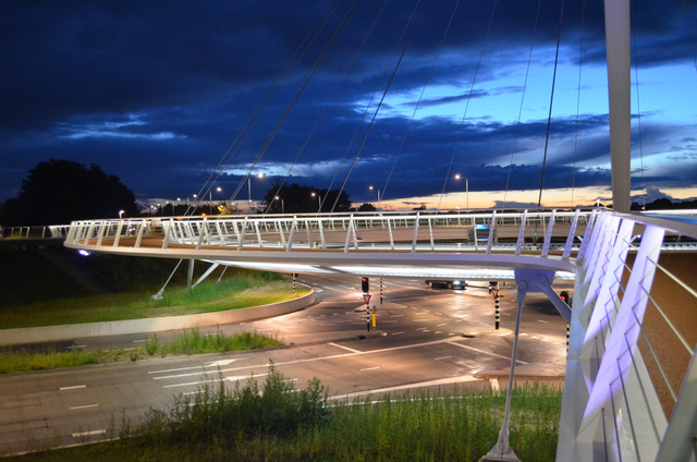 Hovenring’s illuminated circular cycle deck suspended from a central pylon at night.