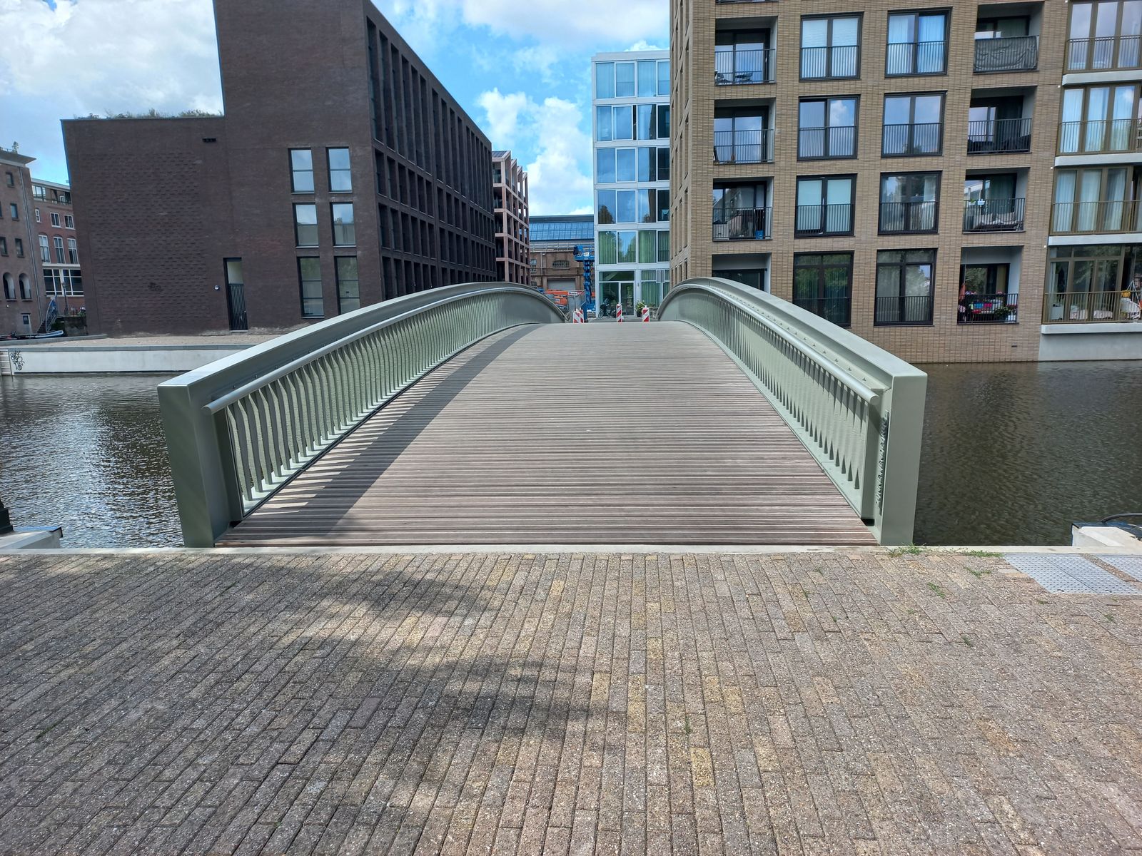 Zonnewendebrug crosses the Oostenburgervaart, with its sequence of individually shaped pale-green balusters visible along both handrails.
